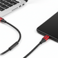 Phone with a charging cable connected to a laptop on a white surface
